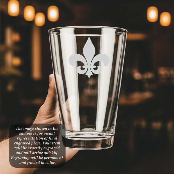 a person holding up a glass with a picture of a fleur de lis
